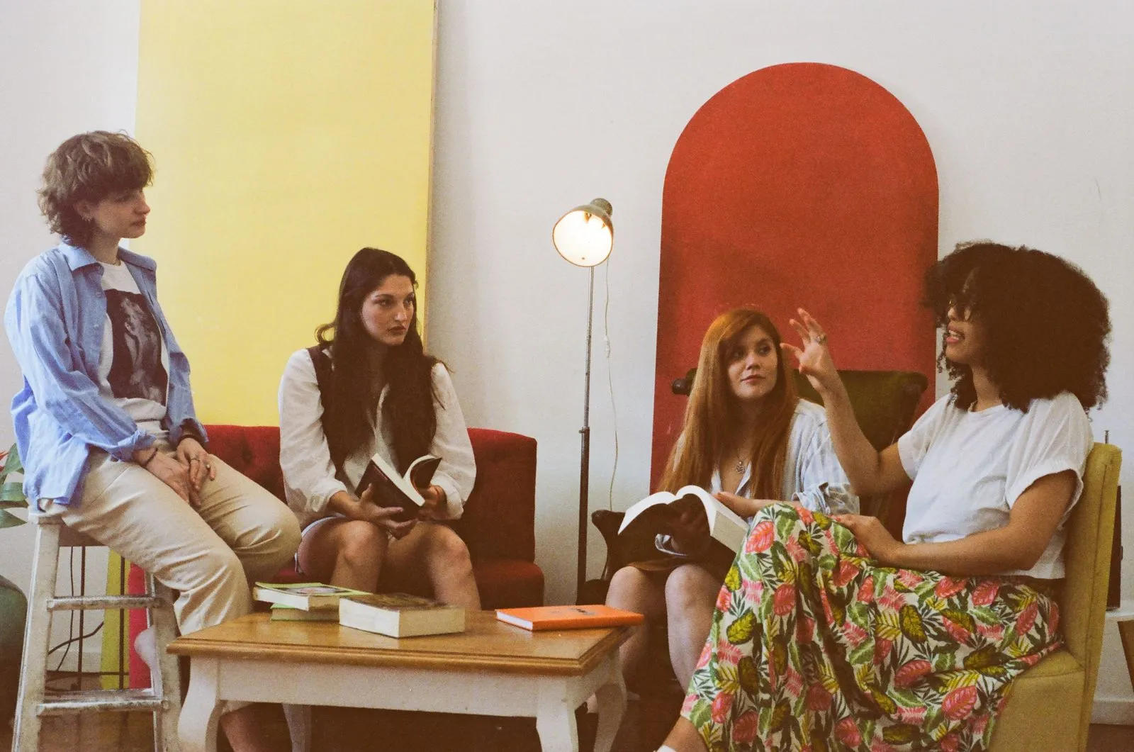 Vier junge Frauen diskutieren mit Büchern in gemütlicher Runde